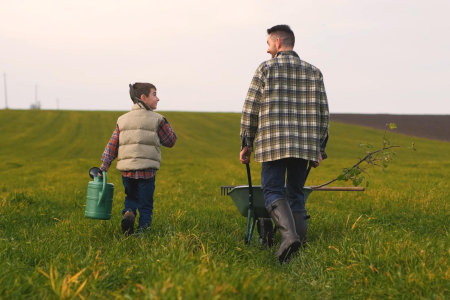 A father and son walk in a field where they grow nursery plants. Blue Meadow is Family Owned & Operated.