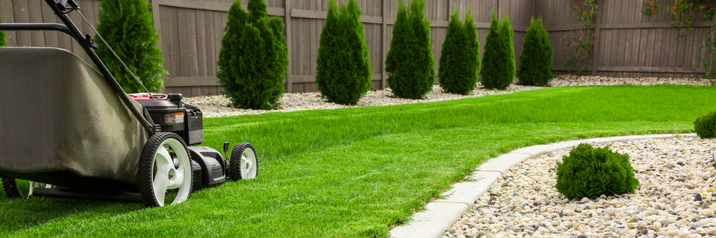 A lawnmower cuts the grass in a well manicured yard demonstrating the landscape services available from Blue Meadow Landscaping in Victoria