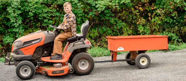 A young teenager drives a lawnmower while pulling a trailer, helping out at the Blue Meadow Landscaping nursery in Victoria, BC.