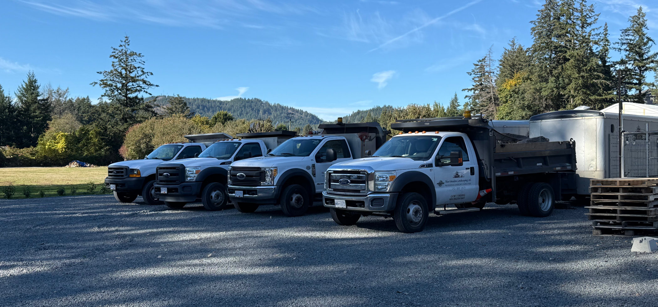 A portion of the Blue Meadow Landscaping truck and trailer fleet is parked on their Victoria lot, ready for work!